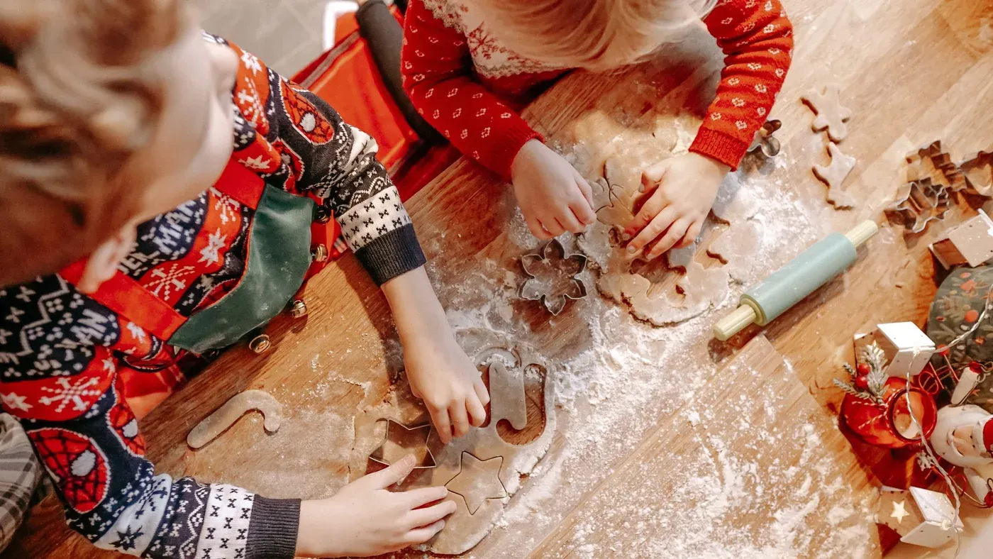 Barnhänder som kavlar och formar pepparkaksdeg på ett mjöligt bord