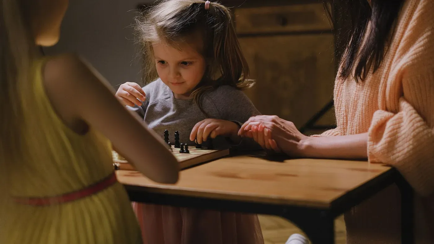 Barn och vuxen som spelar ett brädspel vid ett bord