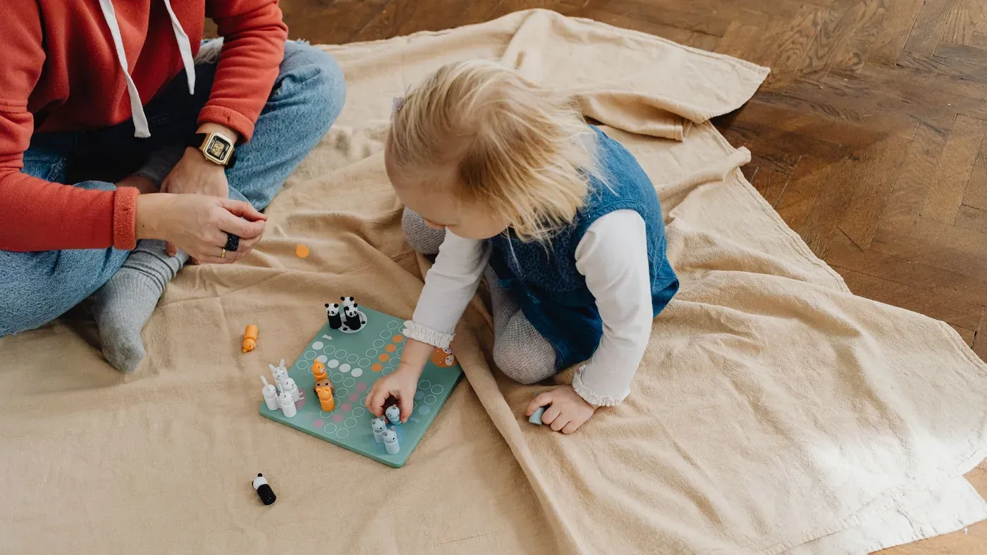 Barn som spelar ett brädspel på en filt
