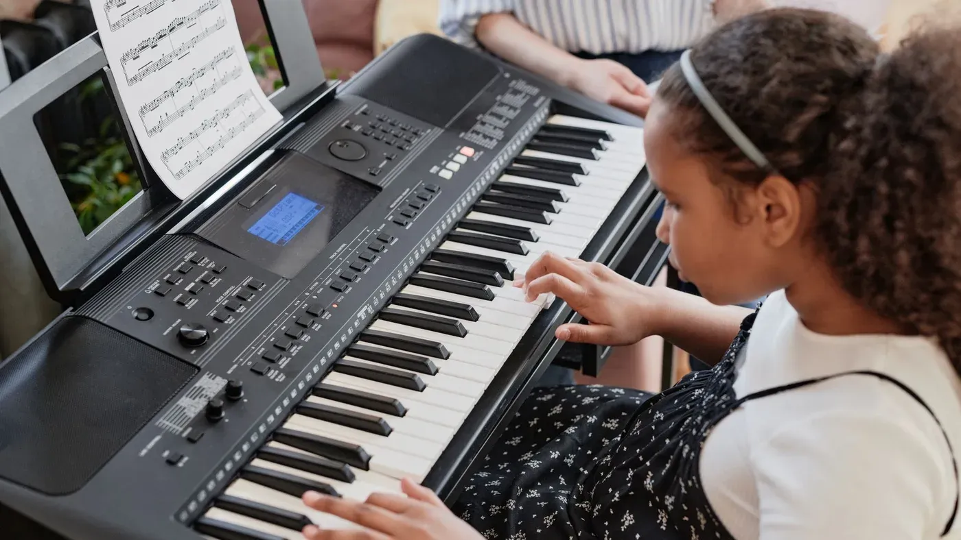 Barn som spelar keyboard med noter framför sig
