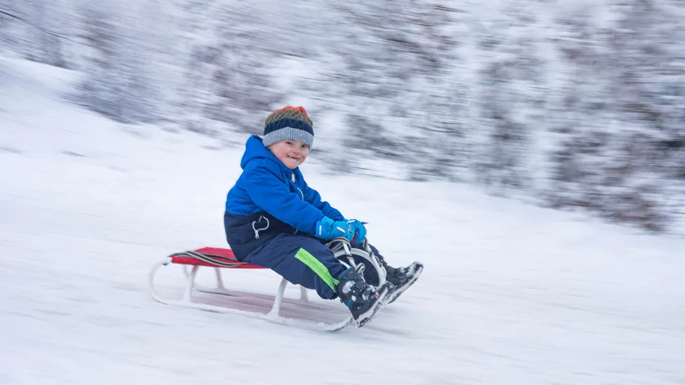 Barn i vinteroverall som åker pulka