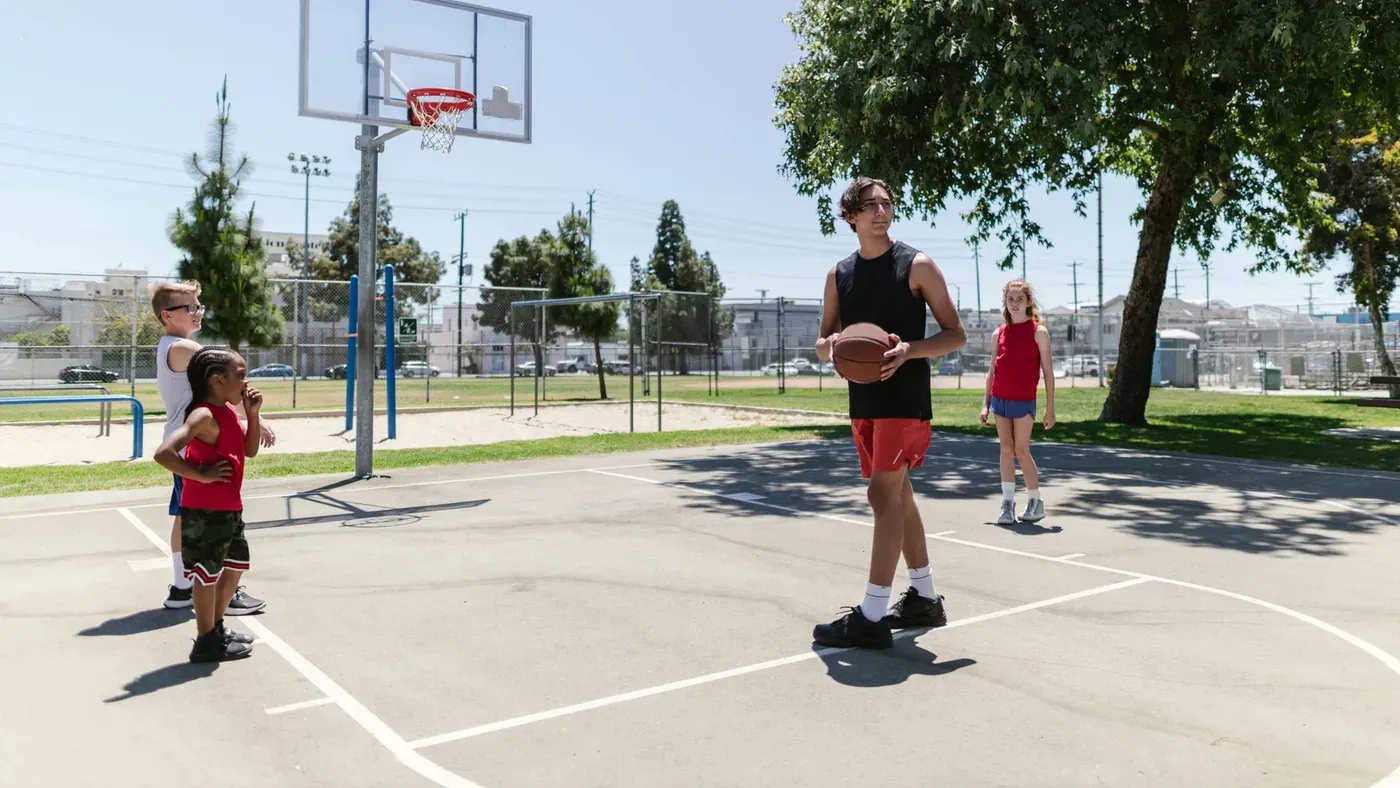 Barn och vuxen på en utomhusplan med basketkorg